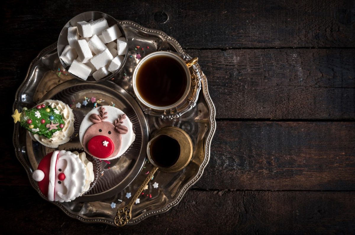 Served Christmas cup cakes with dark coffee on wooden background with empty space